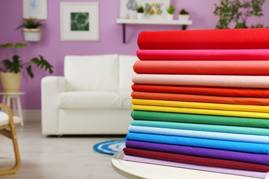 Photo of Pile of colorful t-shirts on table in living room