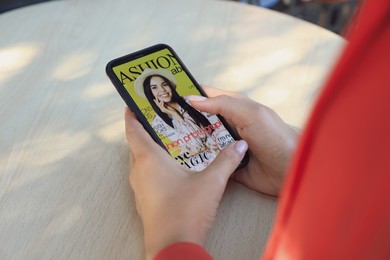 Photo of Woman reading online magazine on smartphone in outdoor cafe, closeup