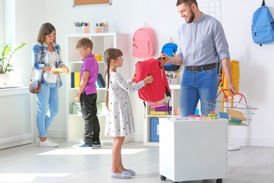 Children with parents choosing school stationery in store