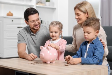 Planning budget together. Family with piggy bank and coins at table indoors