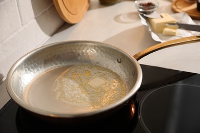 Photo of Frying pan with melted butter on stove, closeup