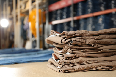 Stack of brown jeans on display in shop