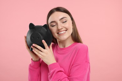 Photo of Happy woman with piggy bank on pink background