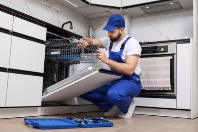 Photo of Serviceman repairing dishwasher cutlery rack in kitchen