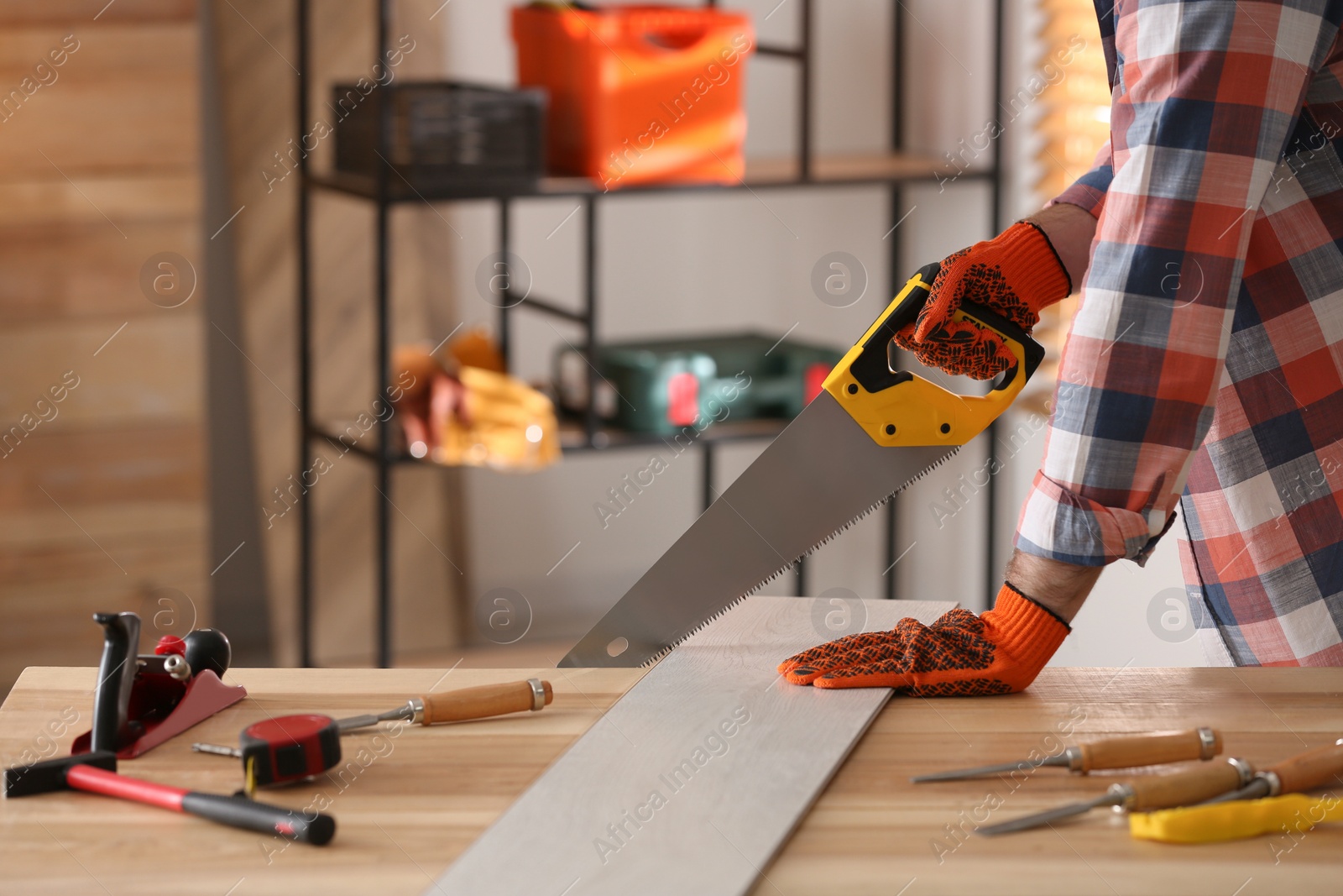 Photo of Carpenter sawing wooden plank at table in workshop, closeup. Space for text