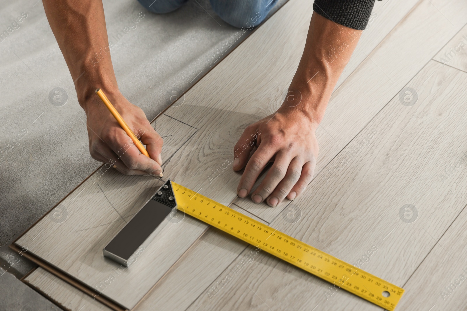 Photo of Worker installing new laminate flooring in room, closeup