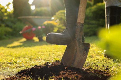 Man digging soil with shovel outdoors on sunny day, closeup. Gardening time