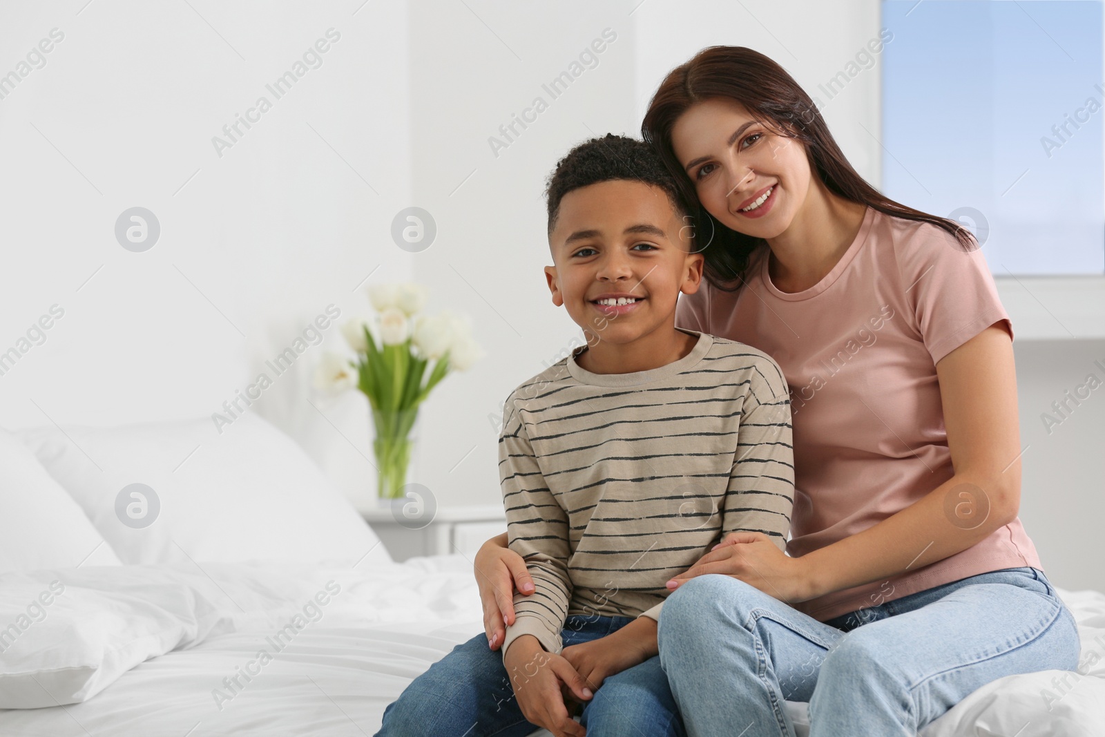 Photo of Mother with her African American son on bed at home. International family