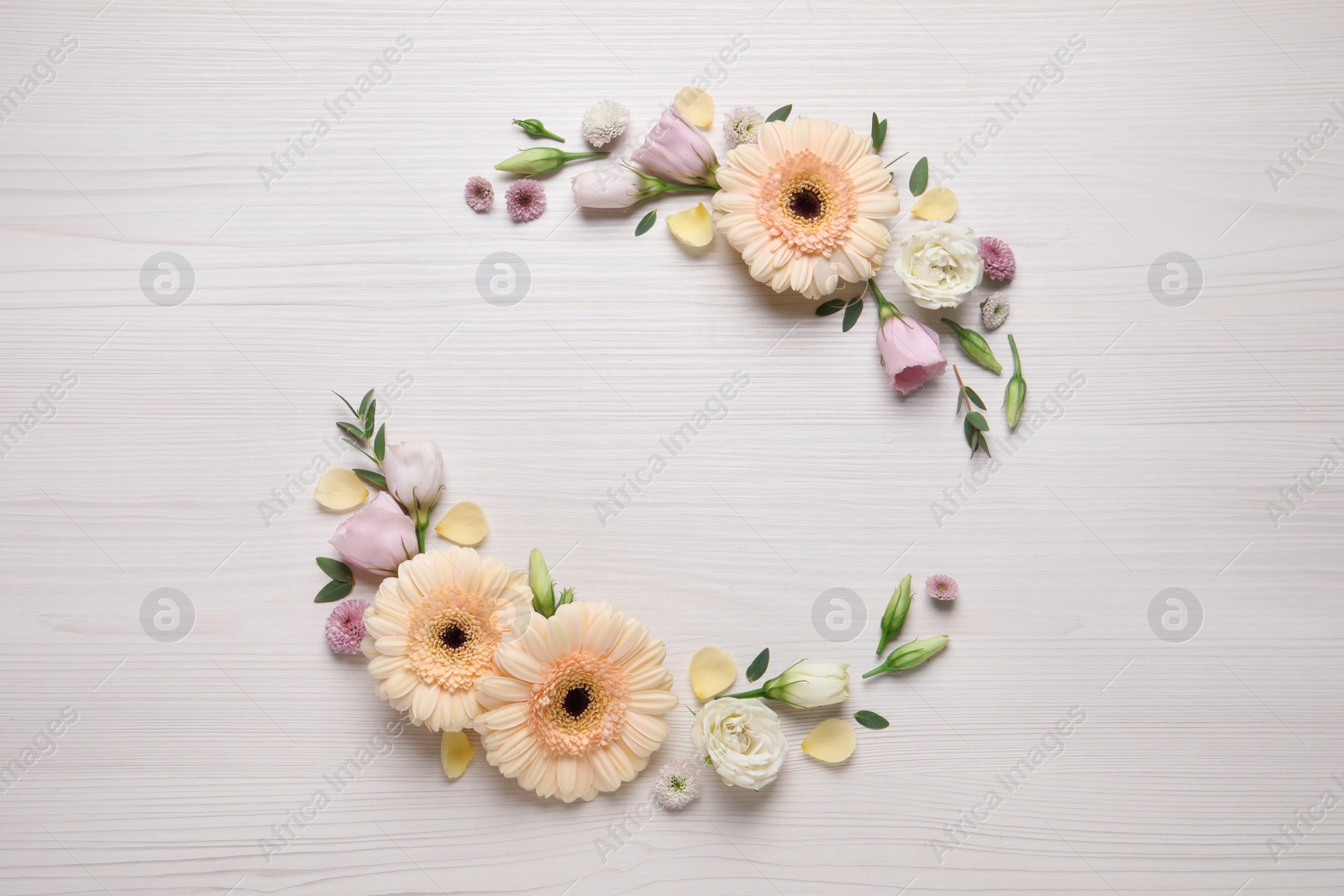 Photo of Wreath made of beautiful flowers and green leaves on white wooden background, flat lay. Space for text