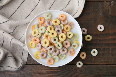 Photo of Cereal rings and milk in bowl on wooden table, top view