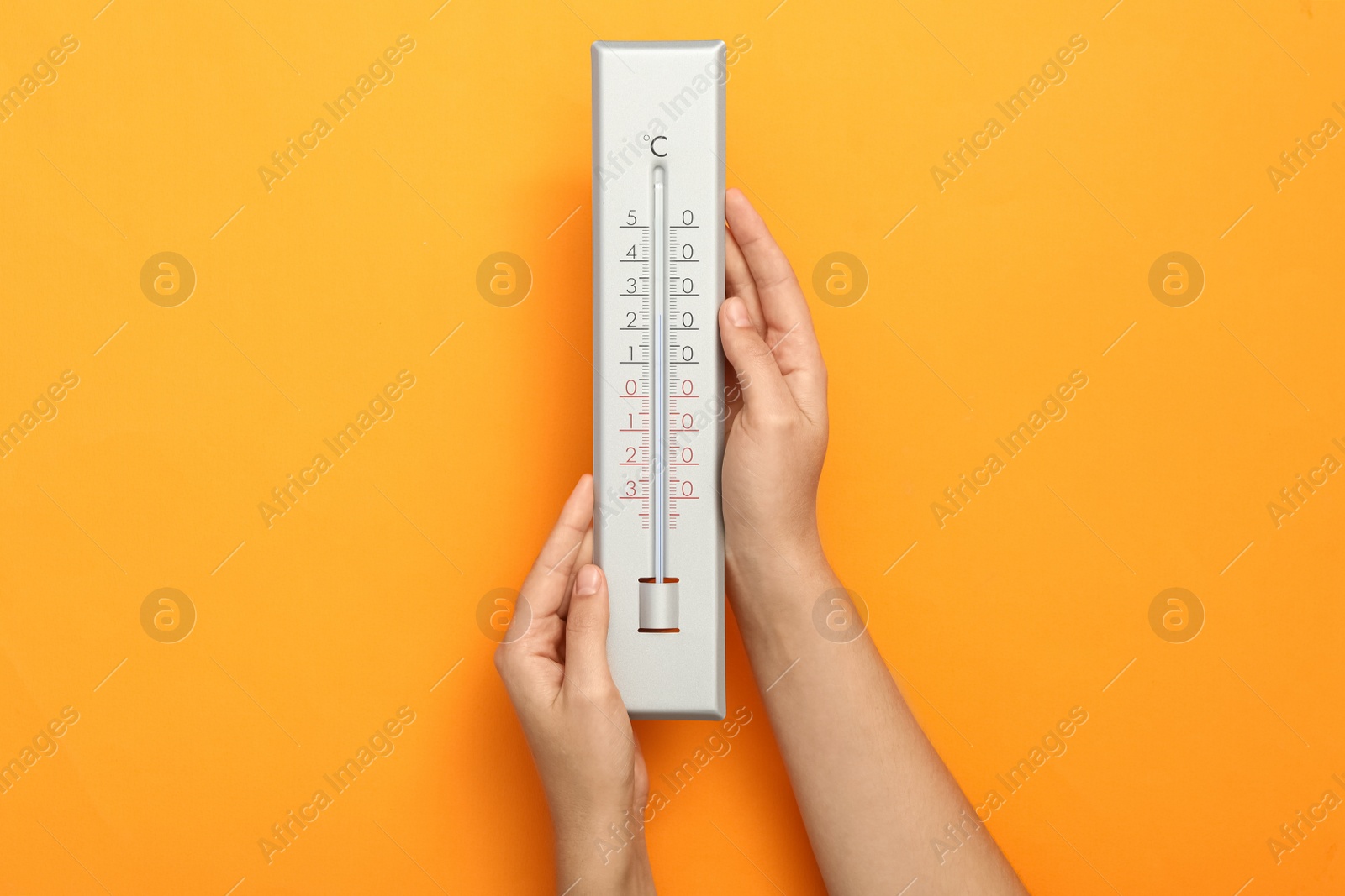 Photo of Woman with weather thermometer on orange background, closeup