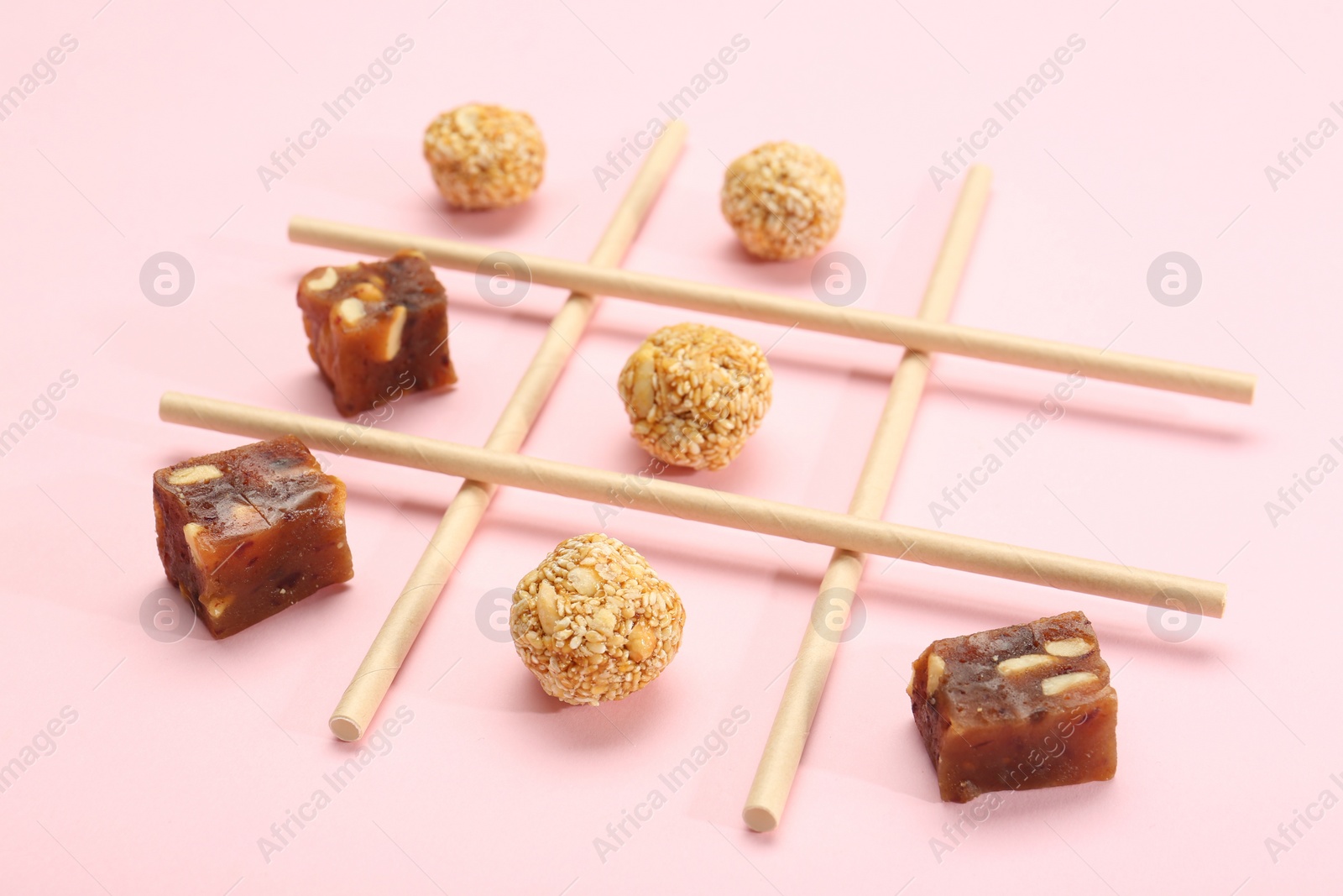 Photo of Tic tac toe game made with sweets on pink background, closeup