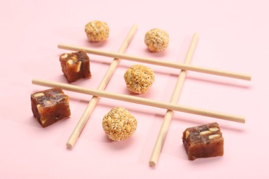 Photo of Tic tac toe game made with sweets on pink background, closeup