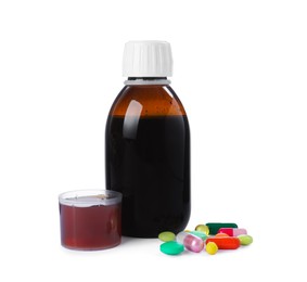 Pills, bottle with measuring cup of syrup on white background. Cough and cold medicine
