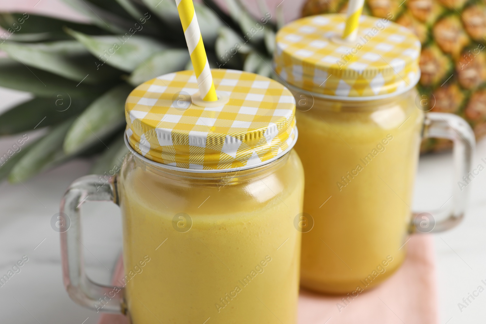 Photo of Tasty pineapple smoothie and fruit on white table, closeup