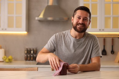 Man packing jar of jam into beeswax food wrap at table in kitchen