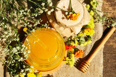 Photo of Delicious fresh honey and beautiful flowers on wooden table, flat lay