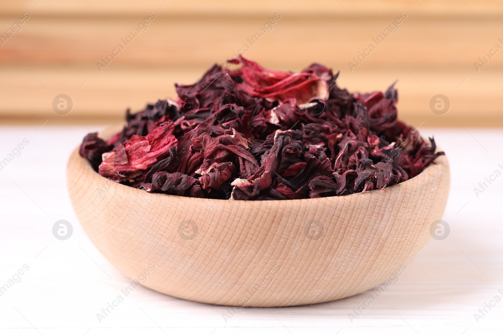 Photo of Dry hibiscus tea in bowl on white table, closeup