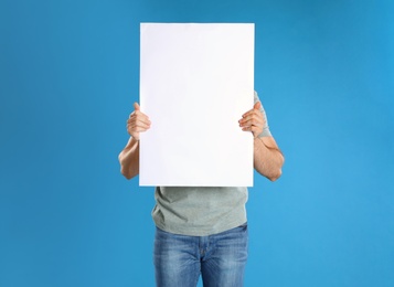 Man holding blank poster on blue background