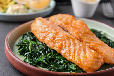 Photo of Tasty salmon with spinach on table, closeup