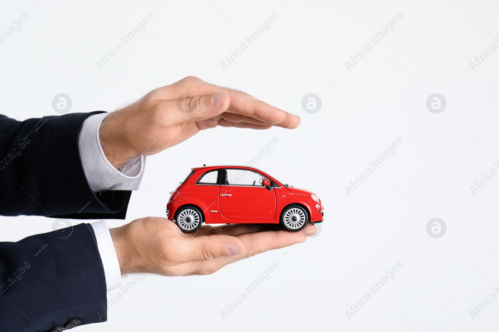 Photo of Male insurance agent holding toy car on white background, closeup. Space for text