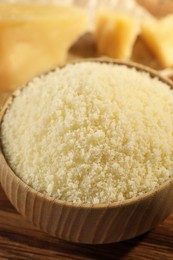 Photo of Bowl with grated parmesan cheese on wooden table, closeup