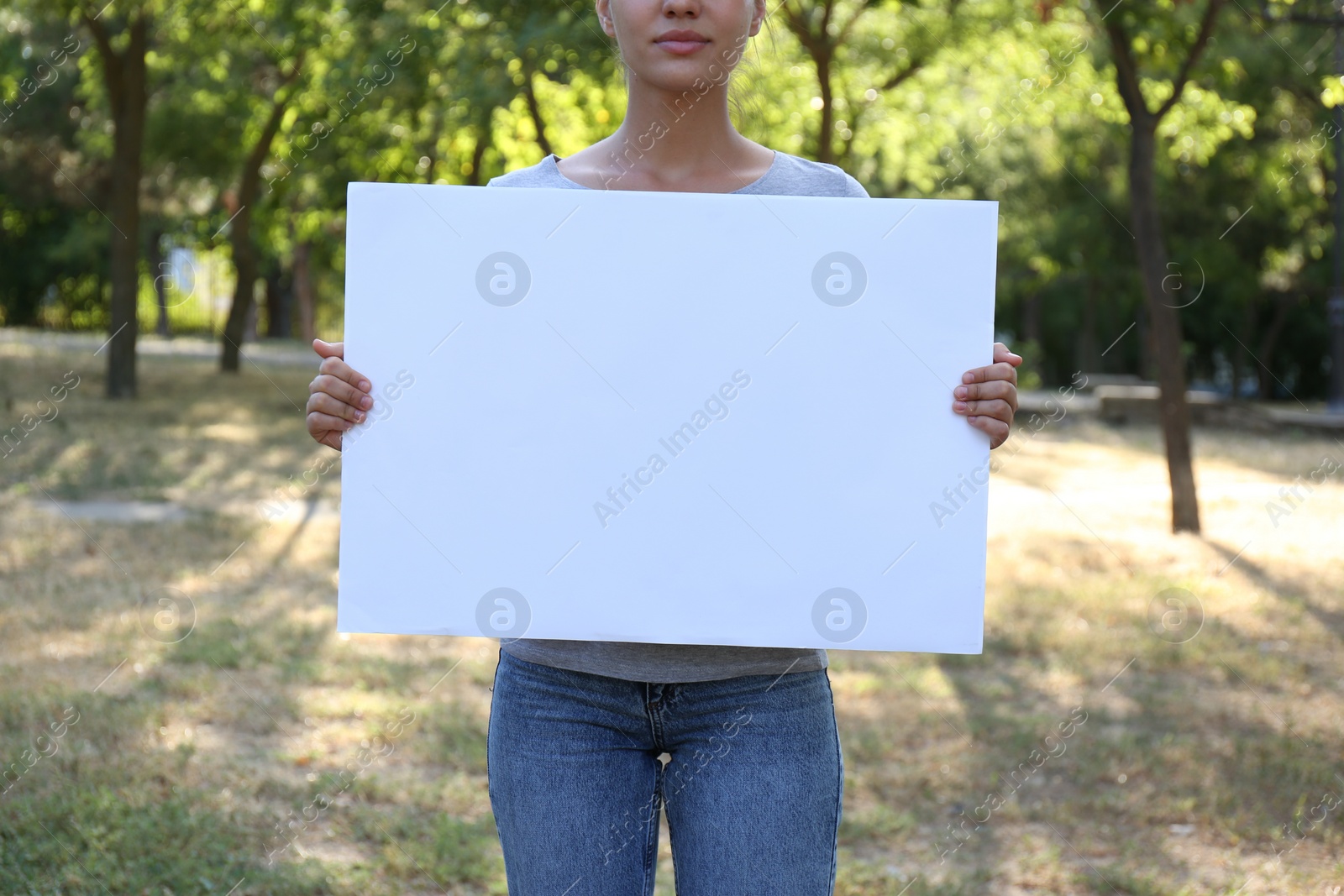 Photo of Woman holding blank poster outdoors, closeup. Mockup for design	