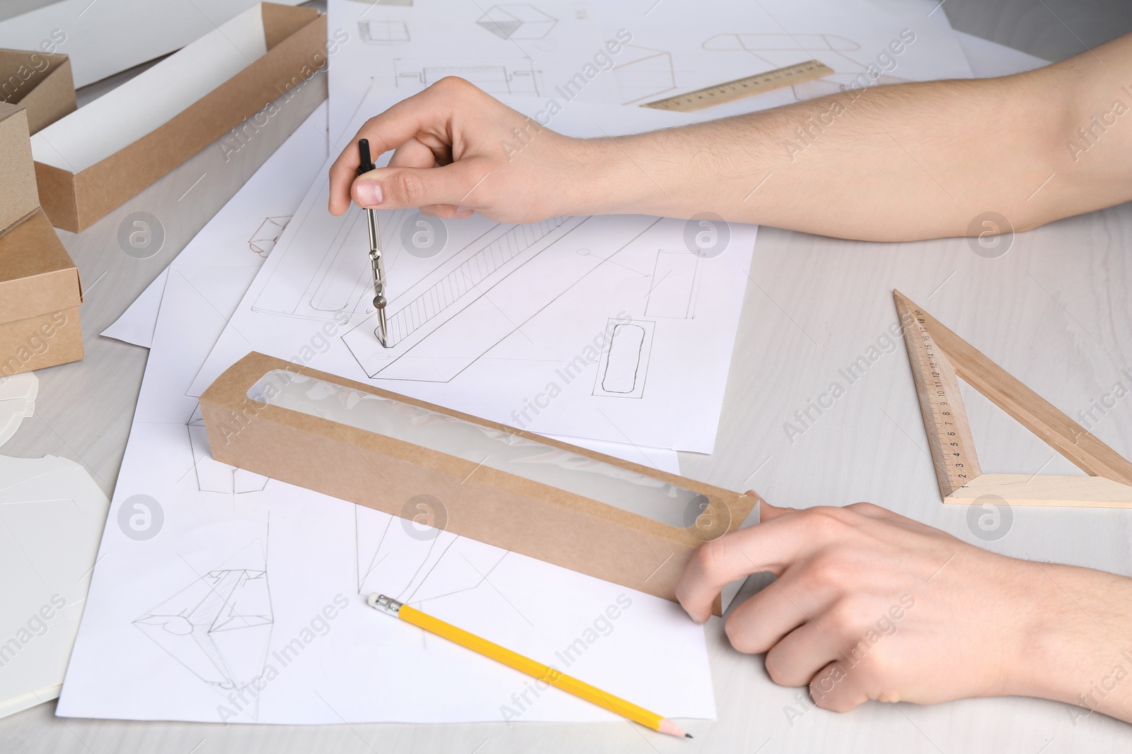 Photo of Man creating packaging design at light wooden table, closeup