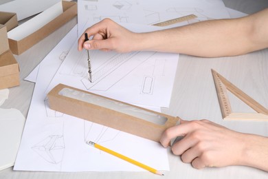 Photo of Man creating packaging design at light wooden table, closeup