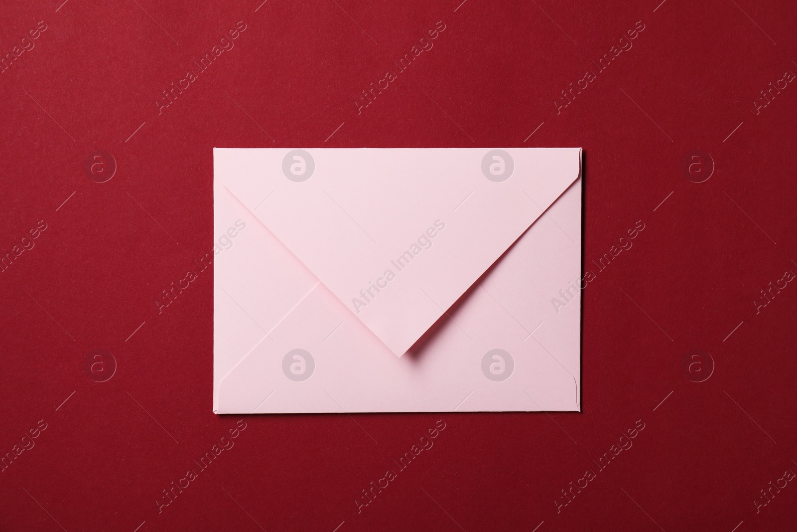 Photo of Letter envelope on red background, top view