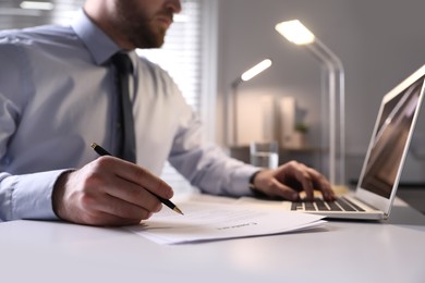 Businessman working with documents at white desk in office, closeup