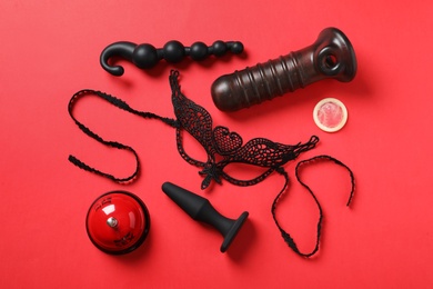 Photo of Different sex toys on red background, flat lay
