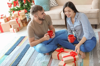 Photo of Happy young couple with Christmas gifts at home