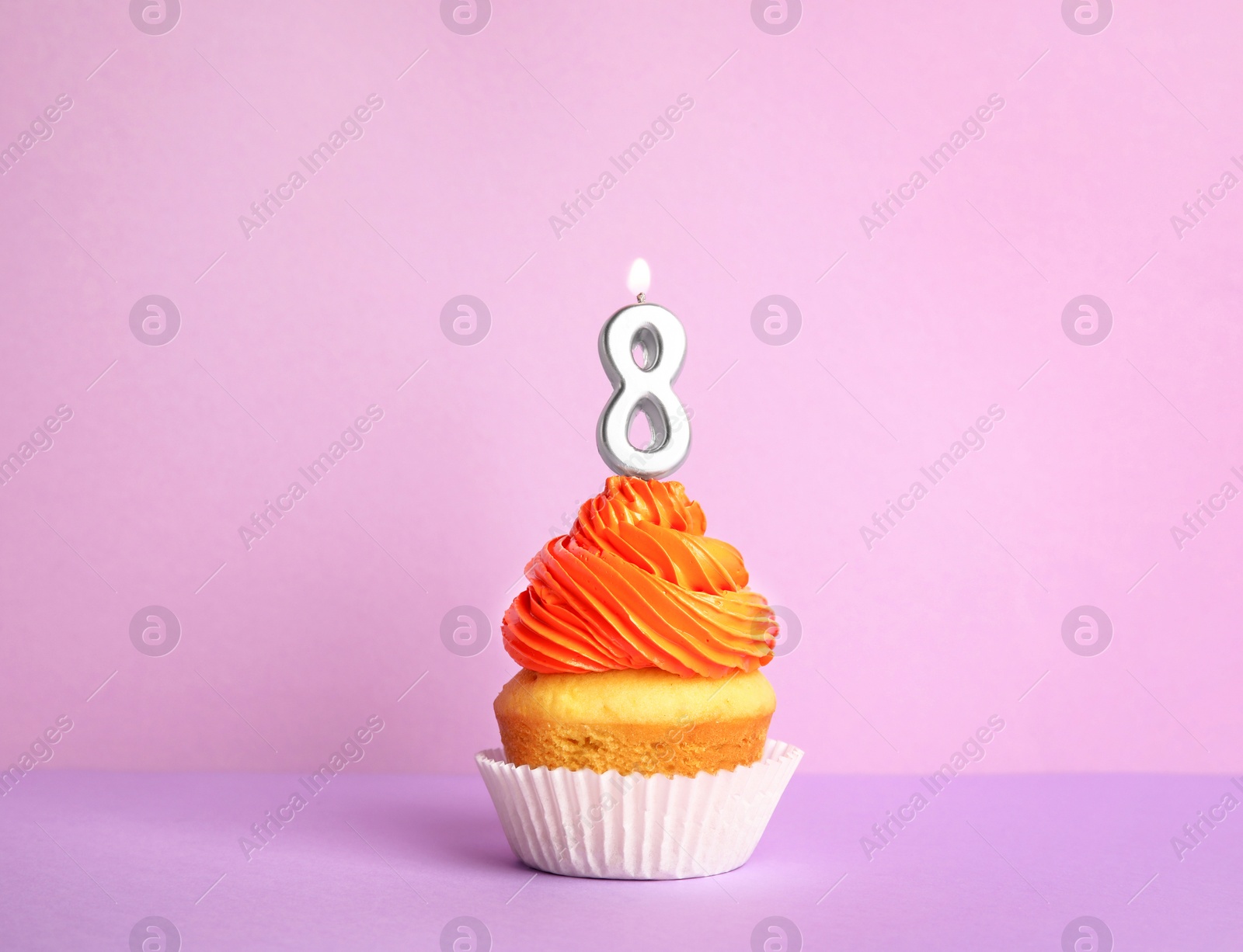Photo of Birthday cupcake with number eight candle on violet background