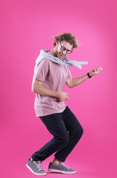 Young man playing air guitar on color background