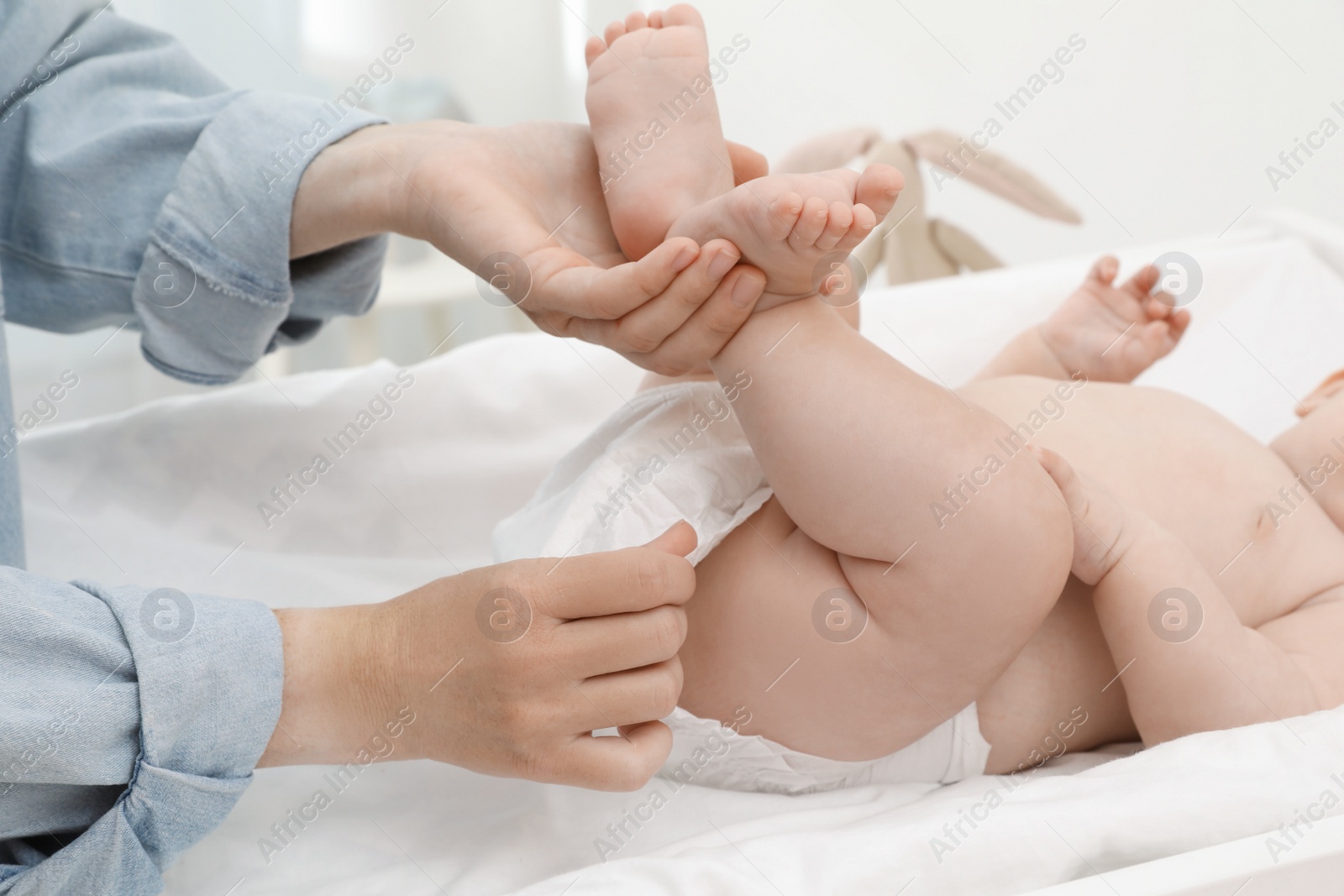 Photo of Mother changing baby's diaper on table at home, closeup