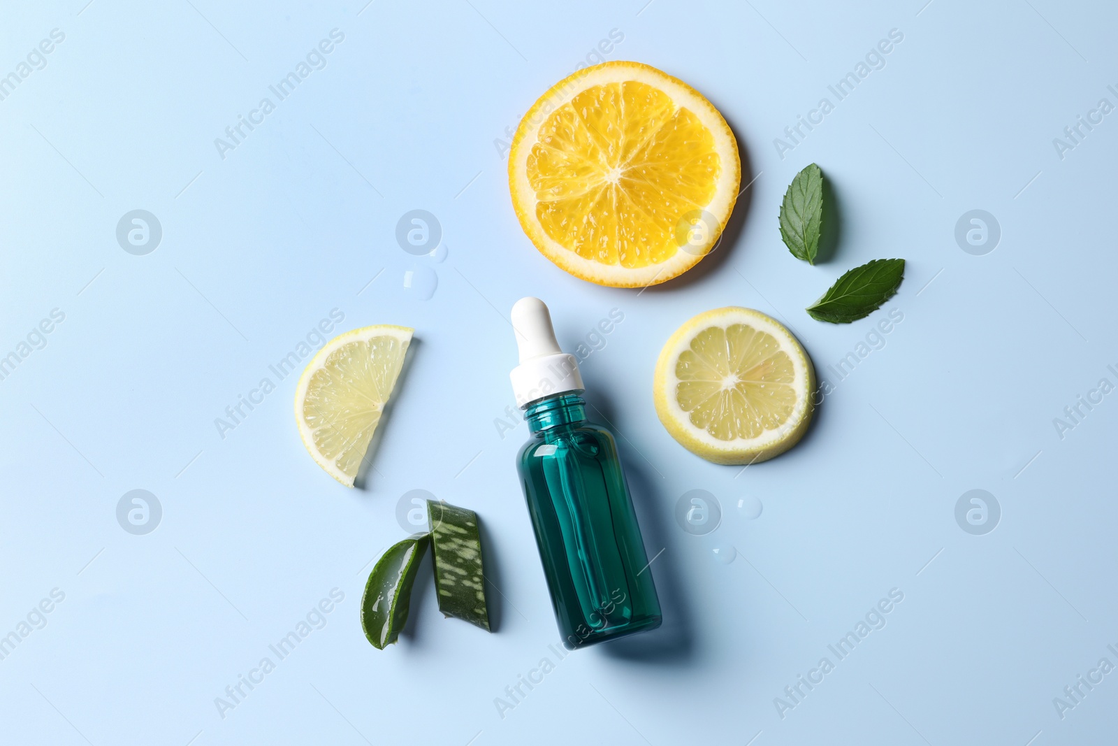 Photo of Bottle of cosmetic serum, sliced citrus fruits and aloe vera on light blue background, flat lay