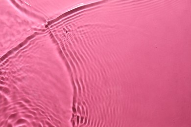 Rippled surface of clear water on bright pink background, top view