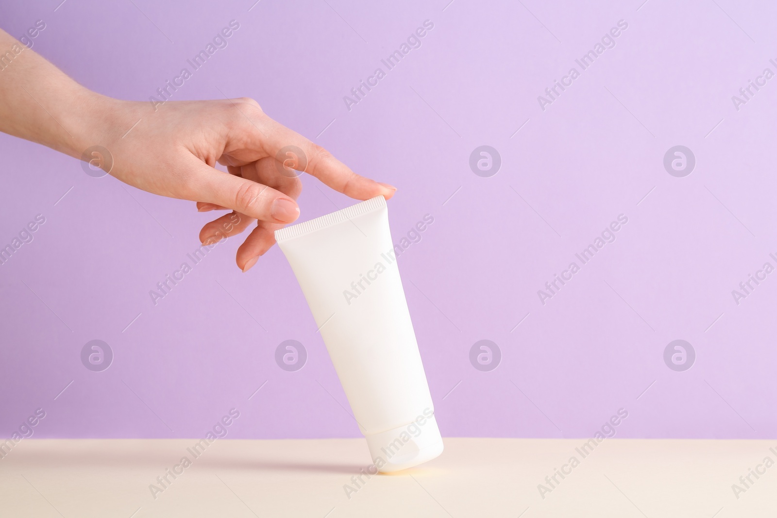 Photo of Woman with tube of cream on lilac background, closeup