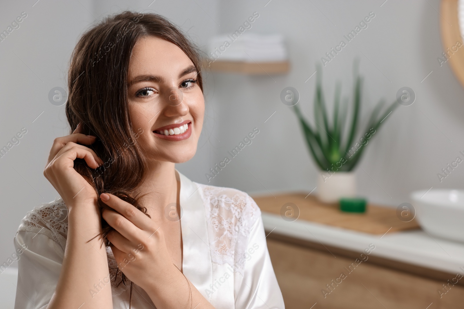 Photo of Young woman applying cosmetic hair mask in bathroom. Space for text