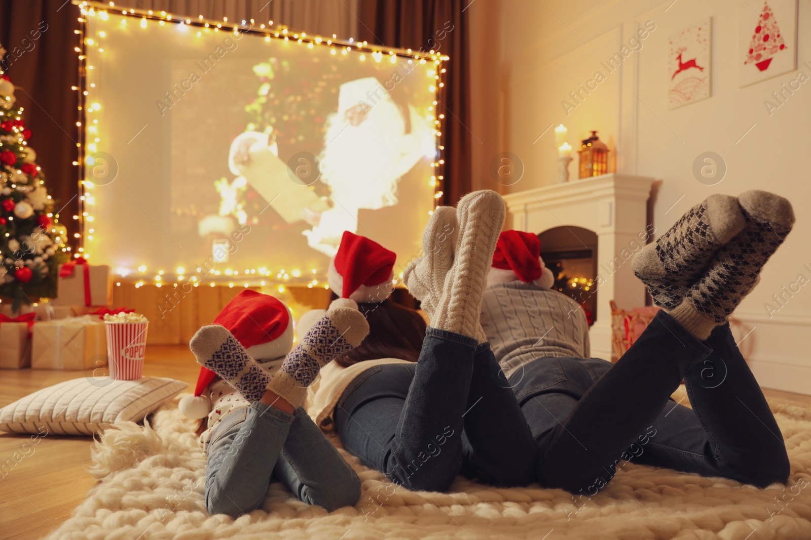 Photo of Family watching movie on projection screen in room decorated for Christmas. Home TV equipment