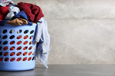 Photo of Laundry basket with clothes near grey wall. Space for text