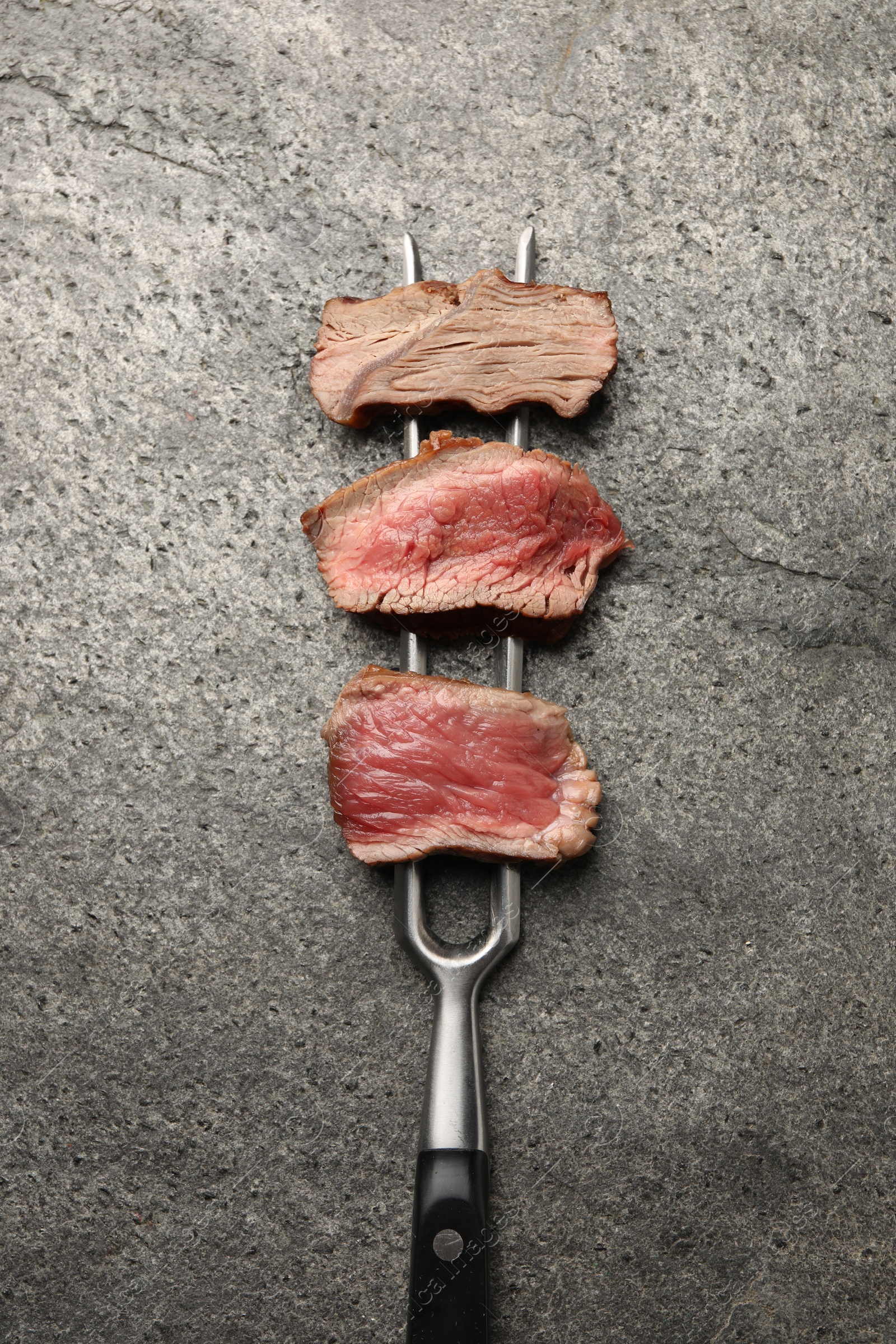 Photo of Delicious sliced beef tenderloin with different degrees of doneness on grey table, top view