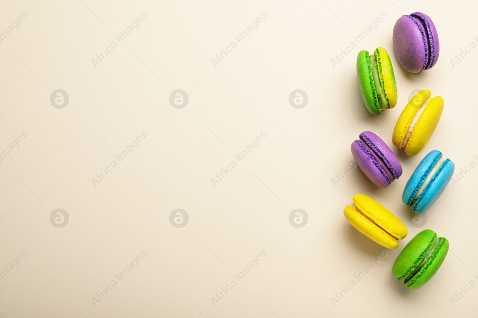 Photo of Delicious colorful macarons on beige background, flat lay. Space for text