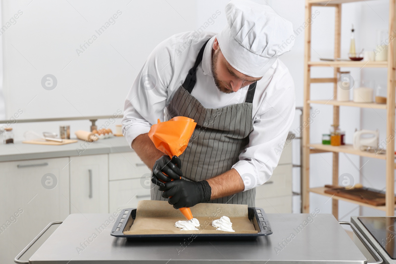 Photo of Pastry chef preparing meringues at table in kitchen