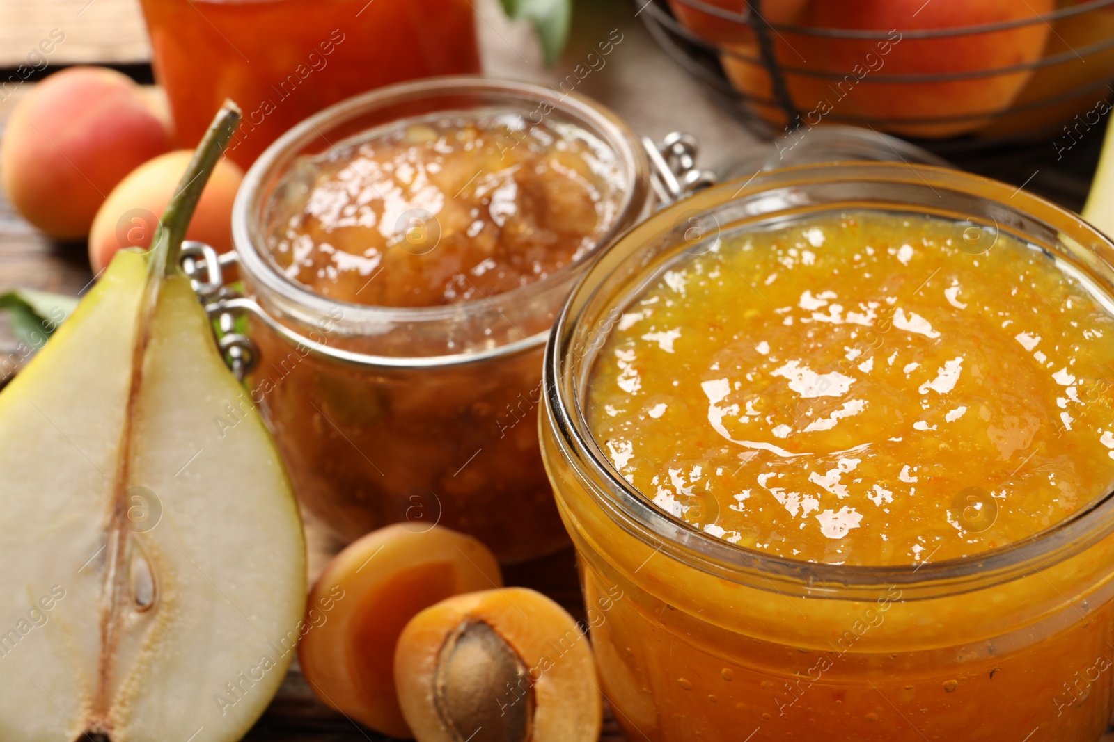 Photo of Jars with different jams and fresh fruits on wooden table, closeup