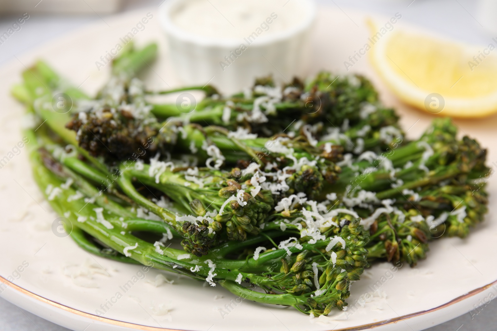 Photo of Tasty cooked broccolini with cheese on plate, closeup