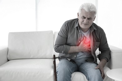 Image of Senior man having heart attack on sofa