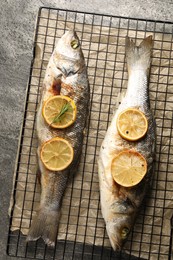 Photo of Baked fish with lemon on grey textured table, top view