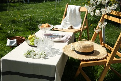 Stylish table setting with beautiful spring flowers in garden on sunny day